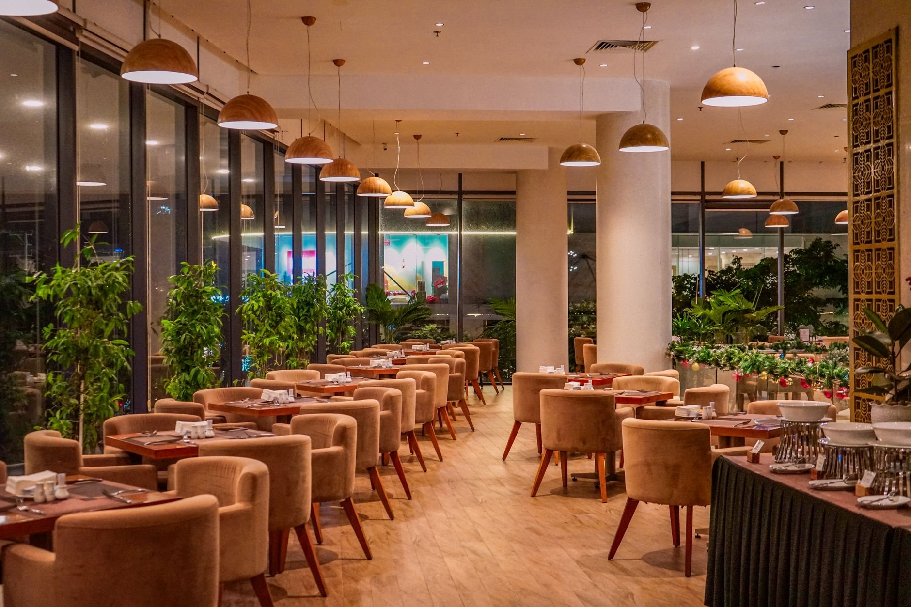 Chic and elegant restaurant interior featuring velvet chairs, wooden tables, and warm lighting.