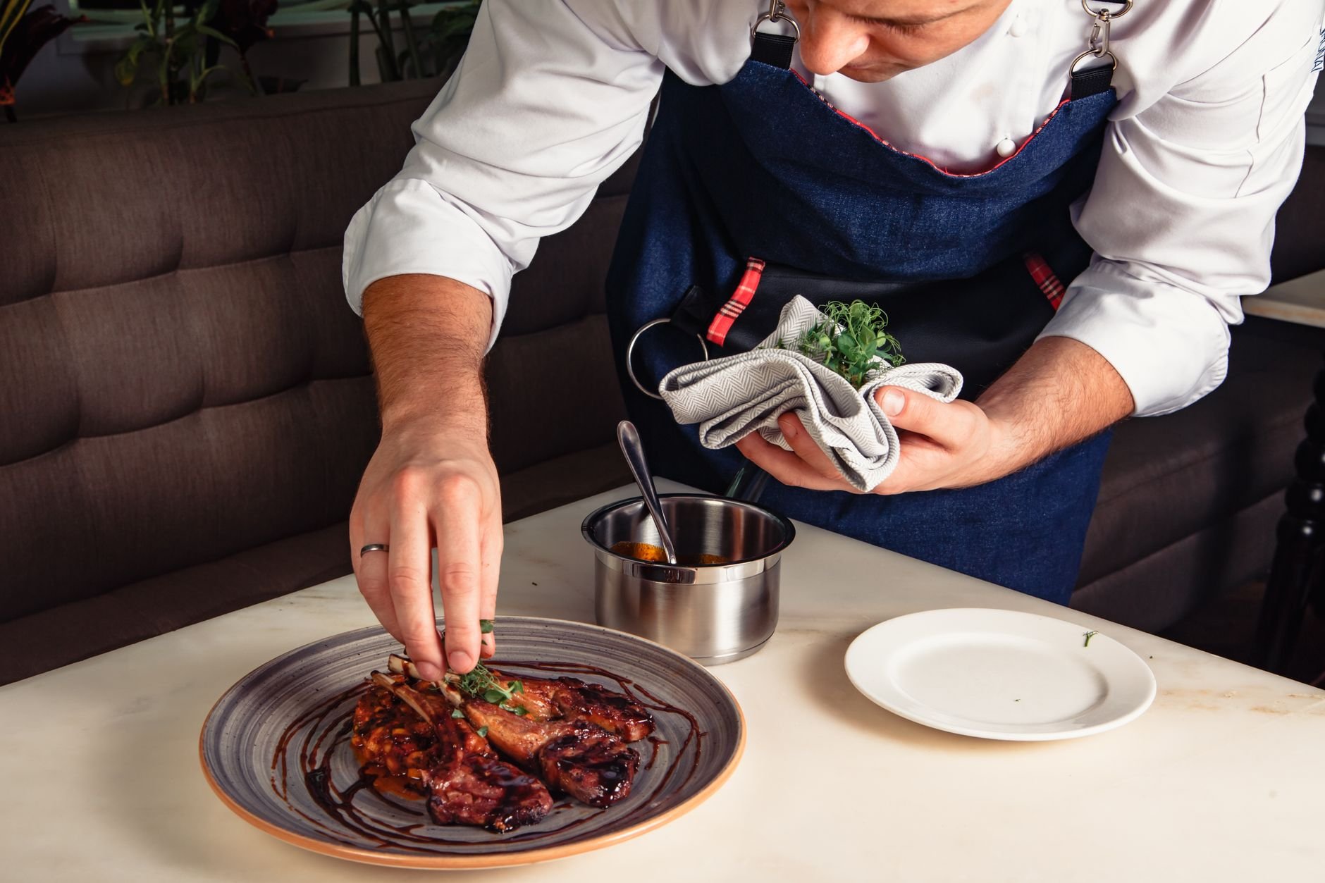 Close-up of a chef plating a gourmet dish in a restaurant kitchen.